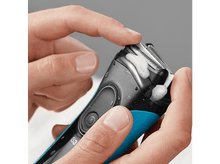 Charger l&#39;image dans la galerie, Mains appliquant de la mousse à raser sur un rasoir électrique noir et bleu.
