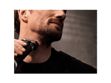 Charger l&#39;image dans la galerie, Un homme se rasant le cou avec un rasoir électrique.
