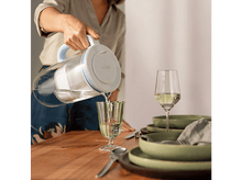 Charger l&#39;image dans la galerie, Une femme versant de l&#39;eau d&#39;une carafe Brita dans un verre.
