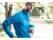 Charger l&#39;image dans la galerie, Un homme en tenue de sport bleue tenant une bouteille d&#39;eau à l&#39;extérieur.
