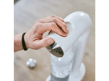 Charger l&#39;image dans la galerie, La main d&#39;une personne appuie sur un bouton d&#39;une machine à soda blanche.
