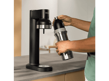 Charger l&#39;image dans la galerie, Une personne remplit une bouteille d&#39;eau en acier inoxydable à partir d&#39;un distributeur noir.
