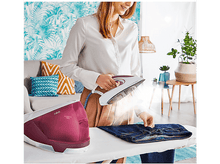 Charger l&#39;image dans la galerie, Femme repassant un jean avec un fer à vapeur, réservoir d&#39;eau rouge visible.
