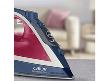 Charger l&#39;image dans la galerie, Gros plan d&#39;un fer à repasser rouge et bleu sur une surface grise, avec un arrière-plan flou de salon.
