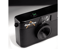 Charger l&#39;image dans la galerie, Appareil photo noir Camp Snap. Bouton vert, logo doré et détail de l&#39;objectif. Fond blanc et noir.

