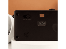 Charger l&#39;image dans la galerie, Appareil photo noir avec interrupteur marche/arrêt/flash, affichage numérique &#39;0723&#39; et haut-parleur. Sur une surface blanche.
