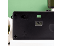 Charger l&#39;image dans la galerie, Dos d&#39;appareil photo noir avec affichage &#39;0723&#39;. Interrupteur flash, éléments verts et haut-parleur. Fond vert.
