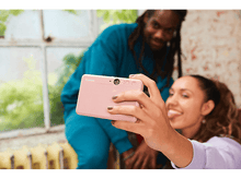 Charger l&#39;image dans la galerie, Deux personnes prennent un selfie avec un appareil photo instantané rose, souriant et posant.
