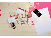 Charger l'image dans la galerie, Articles de scrapbooking sur une table en bois. Comprend des ciseaux, des photos, une imprimante et diverses décorations.
