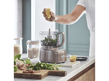 Charger l&#39;image dans la galerie, Une personne pressant un citron au-dessus d&#39;un robot culinaire avec du persil.
