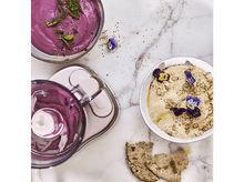 Charger l&#39;image dans la galerie, Vue aérienne d&#39;un robot culinaire et de deux bols de nourriture : un violet, un houmous avec des fleurs.
