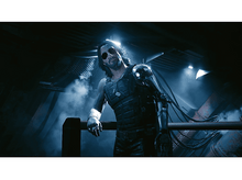 Charger l&#39;image dans la galerie, Un homme portant des lunettes de soleil dans une zone sombre, vêtu d&#39;un débardeur et d&#39;un bras robotique.
