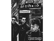 Photo en noir et blanc des membres du groupe Depeche Mode devant une enseigne en bois.