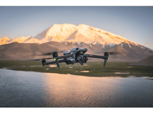 Charger l&#39;image dans la galerie, Un drone volant au-dessus d&#39;un lac avec des montagnes en arrière-plan.
