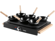 Une surface de cuisson noire avec six petits woks et des poignées en bois, et un bouton de contrôle.