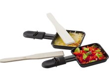 Charger l&#39;image dans la galerie, Deux poêles à raclette avec du fromage et des légumes, accompagnées de spatules en bois, sur une surface blanche.
