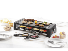 Charger l&#39;image dans la galerie, Gril à raclette avec nourriture sur une table avec assiettes et couverts.
