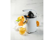Charger l&#39;image dans la galerie, Un presse-agrumes blanc avec du jus d&#39;orange versé dans un verre. Oranges sur la table.
