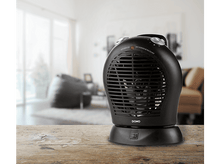 Charger l&#39;image dans la galerie, Chauffage d&#39;appoint DOMO noir sur une table en bois. Arrière-plan flou avec une pièce et des meubles.
