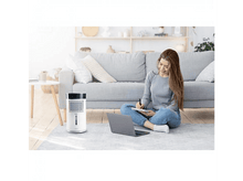 Charger l&#39;image dans la galerie, Une femme écrit sur un bloc-notes tout en étant assise par terre avec un ordinateur portable et un refroidisseur d&#39;air.
