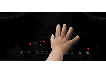 Charger l&#39;image dans la galerie, Main d&#39;enfant touchant une plaque de cuisson noire. Plusieurs icônes de contrôle éclairées sont visibles.
