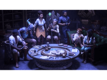 Charger l&#39;image dans la galerie, Groupe de personnes assises autour d&#39;une table, certains tenant des boissons, dans une pièce sombre.
