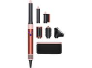 Ensemble de coiffure avec un outil de coiffure or rose et noir et divers accessoires. Fond noir.