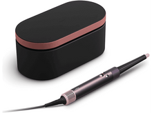 Charger l&#39;image dans la galerie, Un styler capillaire Dyson noir et or rose avec un étui noir sur fond blanc.
