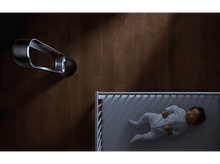 Charger l&#39;image dans la galerie, Un bébé dormant dans un berceau, avec un ventilateur noir au-dessus, sur un sol en bois.
