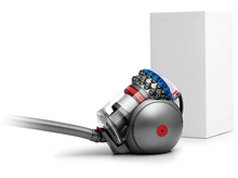 Charger l&#39;image dans la galerie, Aspirateur gris, rouge et bleu avec un tuyau, à côté d&#39;une boîte blanche sur fond blanc.
