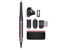 Dyson Airwrap styler avec accessoires, noir et or rose, disposés sur une surface noire.