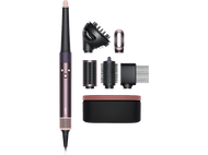 Dyson Airwrap styler avec accessoires, noir et or rose, disposés sur une surface noire.