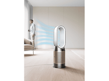 Charger l&#39;image dans la galerie, Un homme se tient près d&#39;un ventilateur blanc et doré. Des flux d&#39;air bleus visibles, sol en bois clair.
