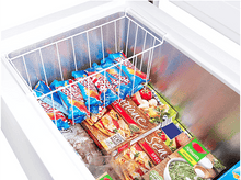 Charger l&#39;image dans la galerie, Un congélateur coffre ouvert rempli d&#39;aliments surgelés comme des pizzas et des bâtonnets glacés dans un panier en fil de fer.
