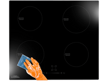 Charger l&#39;image dans la galerie, Une table de cuisson à induction noire avec quatre brûleurs, une main avec des gants orange essuyant la surface.
