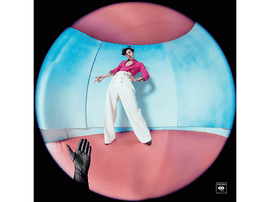 Harry Styles en chemise rose et pantalon blanc, dans une pièce rose et bleue, avec une main.