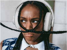 Charger l&#39;image dans la galerie, Une femme avec des tresses portant un casque blanc et un pull à motifs, regardant ailleurs.
