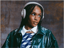 Charger l&#39;image dans la galerie, Une femme portant un casque blanc regarde vers la droite. Elle porte une veste verte et un pull.
