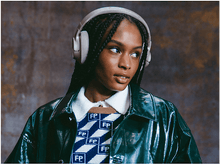 Charger l&#39;image dans la galerie, Une femme avec un casque beige. Elle porte un pull à motifs et une veste verte.
