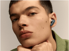 Charger l&#39;image dans la galerie, Un homme avec un écouteur bleu dans l&#39;oreille droite, regardant en avant.
