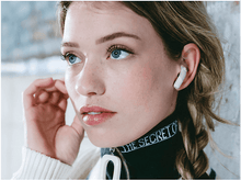 Charger l&#39;image dans la galerie, Femme avec un écouteur blanc dans l&#39;oreille. Porte un col noir avec texte blanc. Yeux bleus.
