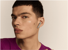 Charger l'image dans la galerie, Homme portant une chemise violette avec un seul écouteur vert dans l'oreille droite.

