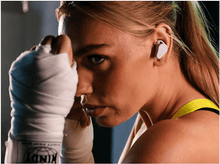 Charger l&#39;image dans la galerie, Une femme portant un écouteur, des gants de boxe et les mains bandées.
