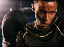 Charger l&#39;image dans la galerie, Un boxeur en chemise noire et gants de boxe, portant des écouteurs blancs.
