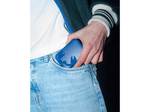 Charger l'image dans la galerie, Une main en jean bleu met une batterie externe bleue dans une poche. Fond noir.
