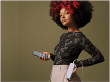 Charger l'image dans la galerie, Femme tenant un téléphone, se chargeant d'une batterie externe violette. Reflets rouges, fond vert olive.
