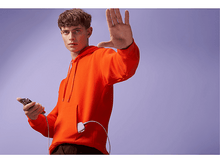 Charger l'image dans la galerie, Un homme portant un sweat à capuche orange tient un téléphone tout en faisant un geste de la main droite. Un chargeur blanc est attaché.
