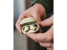 Charger l'image dans la galerie, Mains tenant un étui d'écouteurs vert clair ouvert avec deux écouteurs.
