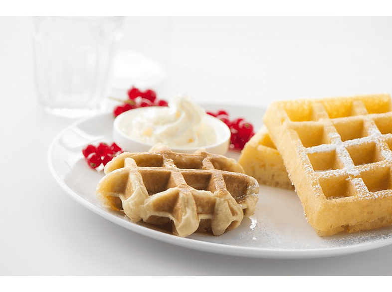 Gaufres avec crème fouettée, groseilles rouges et sucre glace sur une assiette blanche.