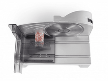Charger l&#39;image dans la galerie, Trancheuse à viande avec une saucisse dans le bac, sur une surface blanche, vue en angle.
